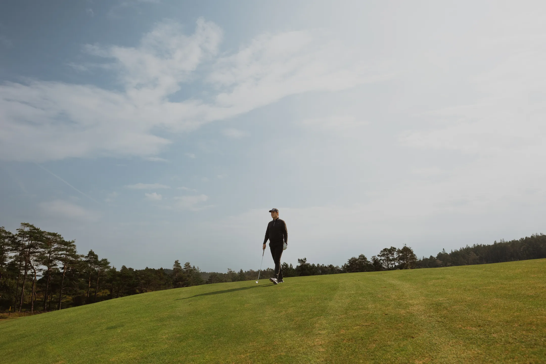 Bård walking on the golf course with an iron club in his hand