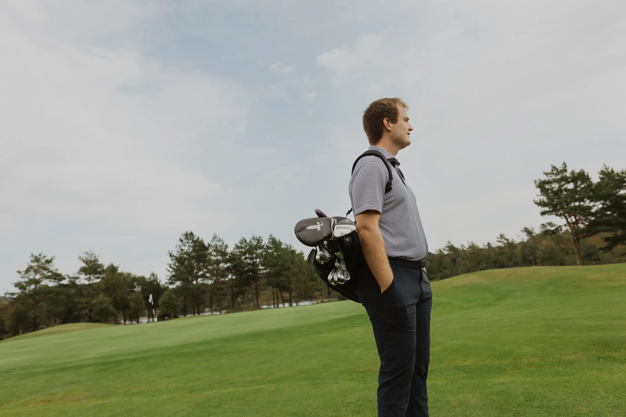 Bård standing on the golf course with the golf bag on his shoulder