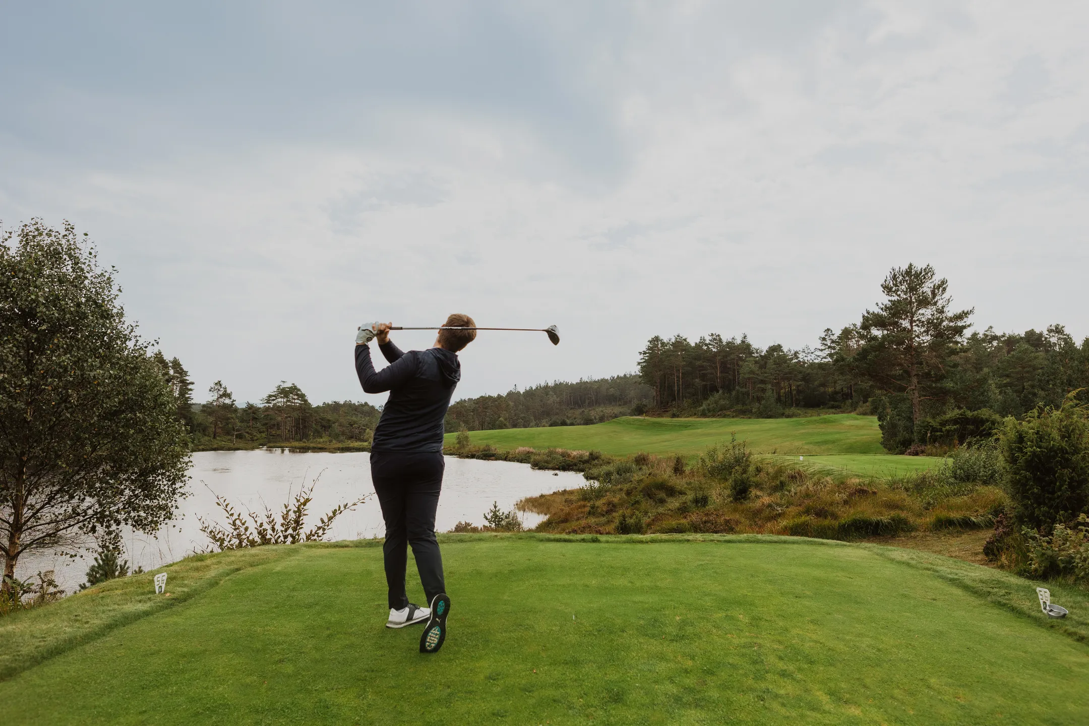 Rear view of Bård on the tee after driving