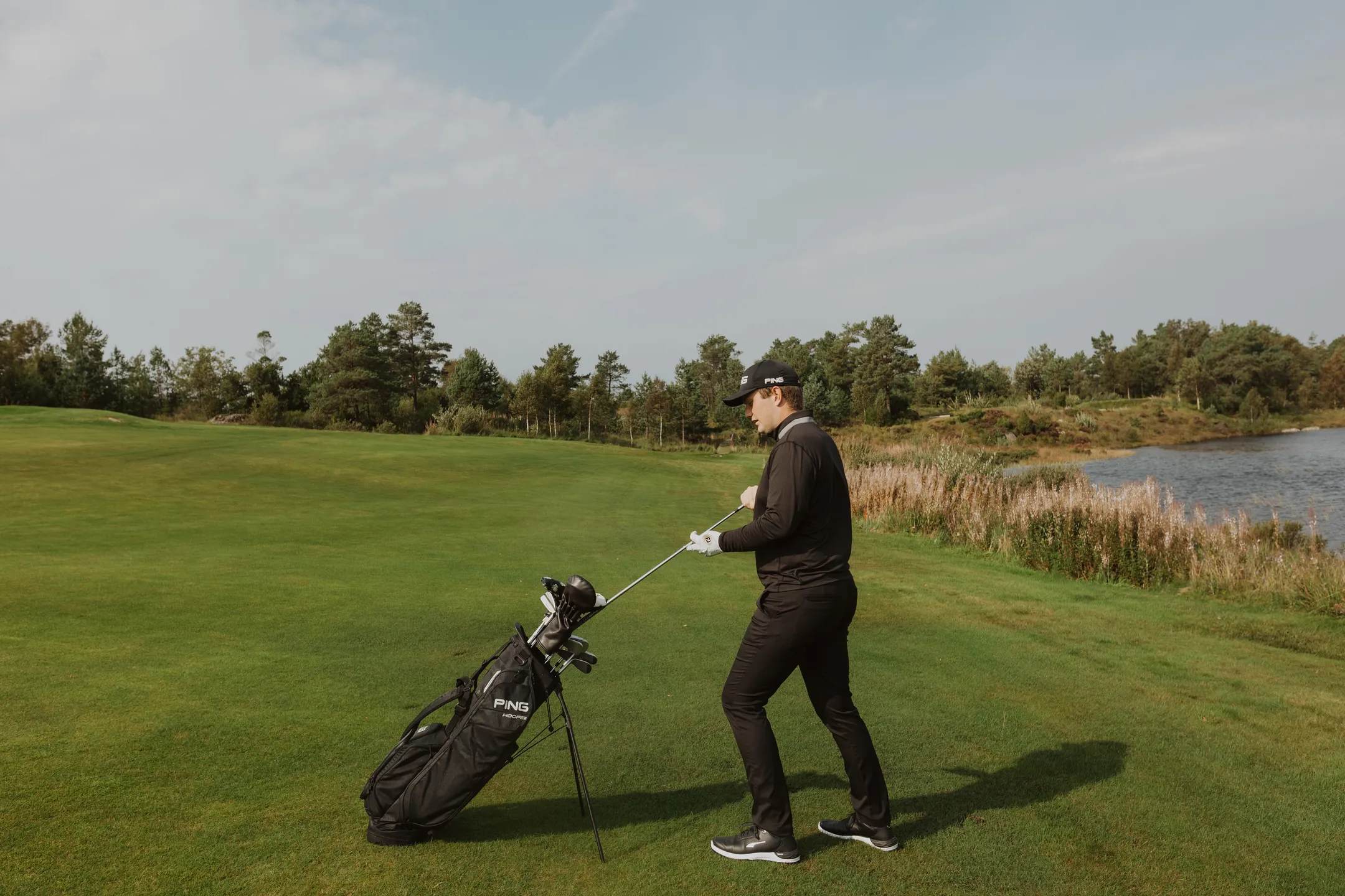 Bård picking up an iron club from his golf bag